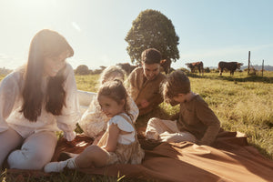 mum and dad sitting on the oimmie picnic blanket with their children