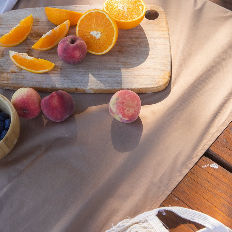 picnic blanket is used as a table cloth with some fruits on it.